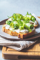 Beautiful toast with cream cheese and cucumber on wooden plate. Beautiful homemade food concept.