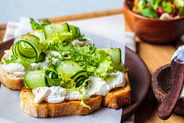 Beautiful toast with cream cheese and cucumber on wooden plate. Beautiful homemade food concept.