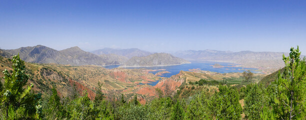Stunning panoramic view of Nurek dam lake on the Vakhsh river, second highest in world between Dushanbe and Khatlon regions in Tajikistan with trees foreground