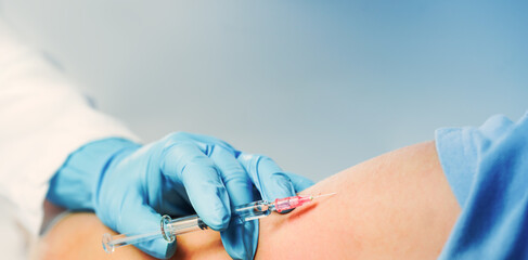 Vaccination. Doctor or nurse hand with glass syringe, needle and child patient arm on blue. copy...