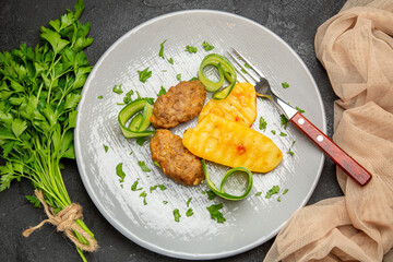 Horizontal view of well-cooked cutlet and a bunch of greens on black table