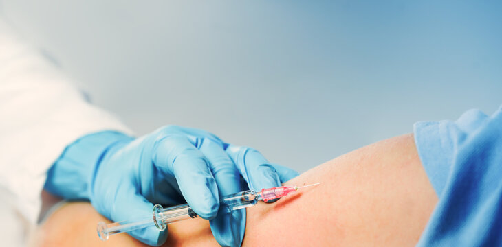 Vaccination. Doctor or nurse hand with glass syringe, needle and child patient arm on blue. copy space. Medication safe consumption and treatment, vaccine and immunization. Health and pharmacy banner