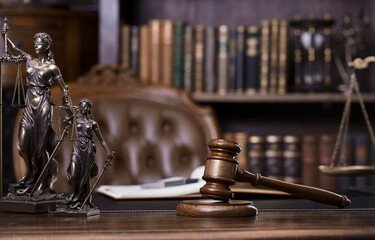 Law and justice theme. Judge chamber. Themis statue, gavel and scale on brown desk. Legal books in...