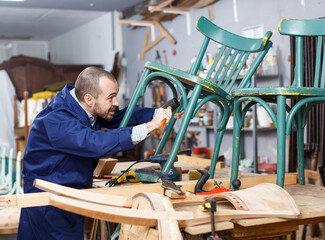 Skilled workman working at repair shop, restoring antique armchair