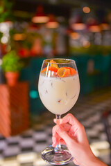 Refreshing white fruit cocktail with orange peels inside. Delicious alcohol drink served in a tall wine glass.