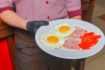 Breakfast - toasts, eggs, bacon served in a cafe or restaurant. Waiter serving breakfast to a customer.