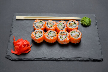 Different Sushi rolls, sushi set rolled in cheese. California philadelphia sushi rools served on a black chalk board.