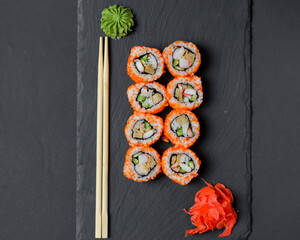 Different Sushi rolls, sushi set rolled in cheese. California philadelphia sushi rools served on a black chalk board.