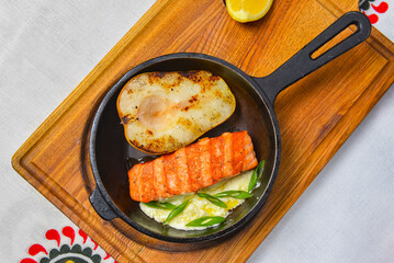 Fototapeta na wymiar Salmon steak grilled with half a pear served in a pan over wooden board. Ukrainian cuisine concept.