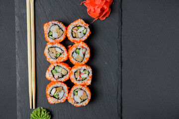 Different Sushi rolls, sushi set rolled in cheese. California philadelphia sushi rolls served on a black chalk board.