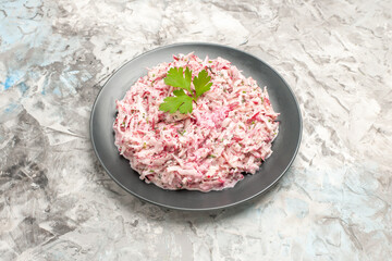 Top view of delicious salad decorated with green on a black plate on ice background