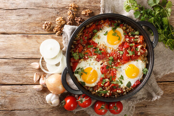 Adjarian breakfast Chirbuli of fried eggs with tomatoes, onions and walnuts close-up in a frying pan on the table. horizontal top view from above