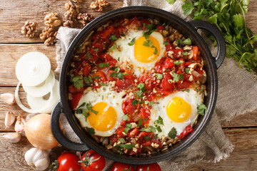 Chirbuli is a staple of the Georgian breakfast table consisting of fried eggs with tomatoes, onions and walnuts close-up in a frying pan on the table. horizontal top view from above