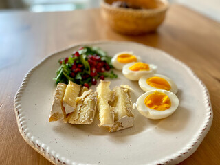 Healthy Homemade Breakfast Plate with Moldy Cheese, Boiled Eggs, Rucola Arugula or Rocket Leaves with Pomegranate Seeds on Wooden Table.