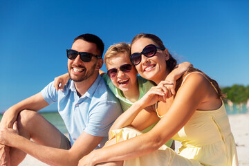 Obraz premium family, leisure and people concept - happy mother, father and little son hugging on summer beach