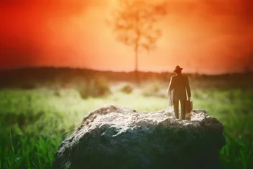 Surreales Bild eines mysteriösen Mannes, der während des Sonnenuntergangs allein auf dem Feld spaziert © tomertu