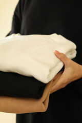 Young woman in black sweatshirt hold three sweatshirts