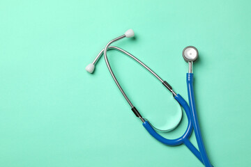 Blue stethoscope on mint background, space for text