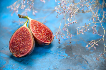 Front close view of fresh black mission figs on the right side on blue background
