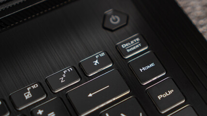 Flight mode button, F12 key, airplane button on keyboard. Laptop flat profile backlit keyboard airplane flight mode key closeup