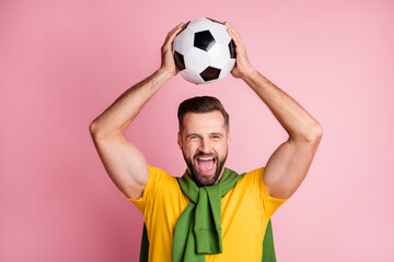 Photo of happy soccer man fan hold ball above head celebrate win isolated on pastel pink color background