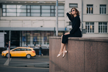 Fototapeta premium Young woman in black dress sitting, have a break in city