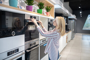 Blonde customer choosing oven in a showroom