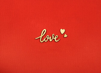 Fototapeta na wymiar Lettering love and wooden hearts on red paper