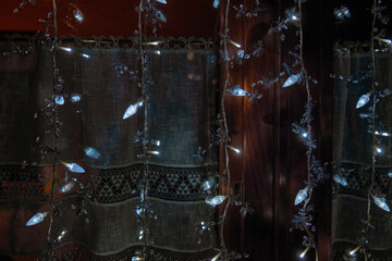 White Christmas lights in front of a larch window with lace curtains