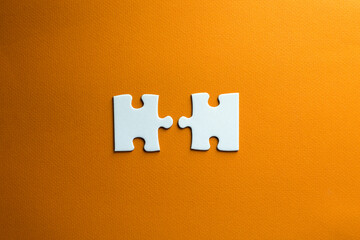two pieces of a puzzle do not fit together. white pieces on an orange background. conceptual photo...