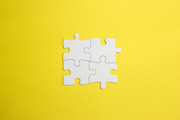 4 pieces of a puzzle fit together to form a team. white pieces to make an idea in the form of a drawing, word or concept fit together. yellow background