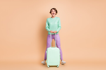 Full size photo of young girl excited amazed surprised trip tourist vacation abroad hold baggage isolated over beige color background
