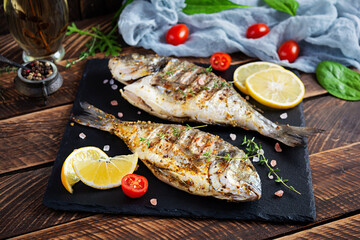 Grilled dorado fish on wooden background. Roasted seafish with spice and herbs