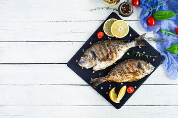 Grilled dorado fish on wooden background. Roasted seafish with spice and herbs