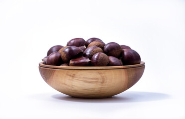 Chestnuts in a wooden bowl on white background. Castanea sativa, sweet ripe Chestnuts