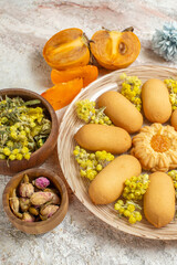 a view of a plate of cookies and palms and bowls of dry flowers on dusty pink background