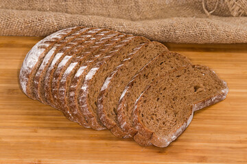 Sliced wheat rye brown bread on a wooden surface