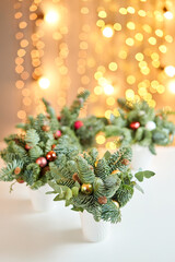 Christmas arrangement with Norwegian pine Nobilis and decorated with Christmas decor in a ceramics Cup. Garland bokeh on background. Christmas love. Dark wooden table sprinkled with snow