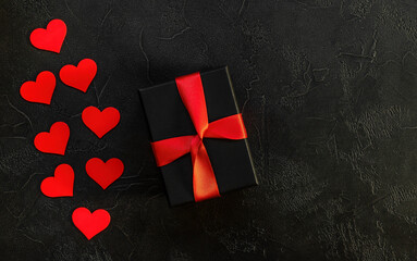 Valentine's day romantic concept. Red wooden hearts and giftbox on black background.