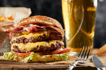 The concept of American fast food. A juicy American burger with two beef patties and a dark beer on...