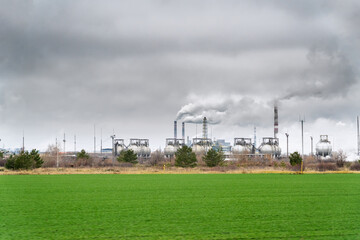 View of a chemical plant with Smoking chimneys against a dark cloudy dirty sky