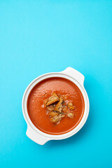 tomato soup in white bowl on blue background