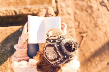 beautiful woman with cap reading a book in a park at winter or spring sunset. concept lifestyle relaxation
