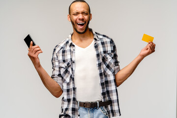 Portrait of a young african american man holding mobile cell phone and credit or discount card