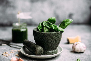 Cooking pesto sauce in stone mortar on gray background