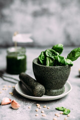 Cooking pesto sauce in stone mortar on gray background