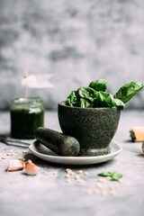 Cooking pesto sauce in stone mortar on gray background