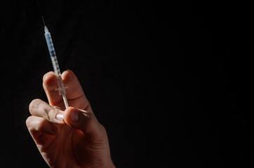 Hand with injection syringe on black background