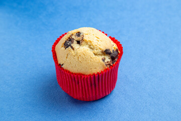 Top view of freshly baked small cupcake with chocolates on blue background