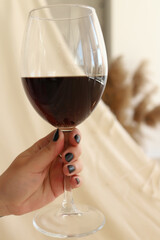 a glass of red wine in the hands of a girl